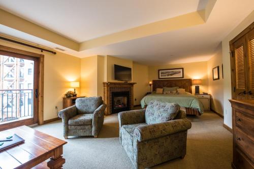 a bedroom with a bed and two chairs and a fireplace at The Lodge at Mountaineer Square in Mount Crested Butte