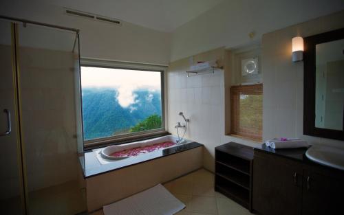a bathroom with a window with a sink and a shower at After the Rains - Rainforest Lodge in Meppādi