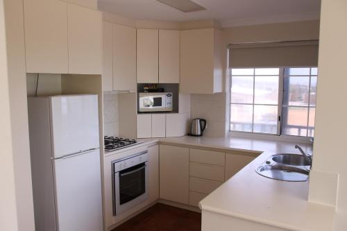 a kitchen with a white refrigerator and a sink at Seaspray Beach Holiday Park in Dongara