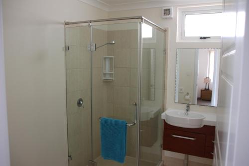 a bathroom with a glass shower and a sink at Seaspray Beach Holiday Park in Dongara