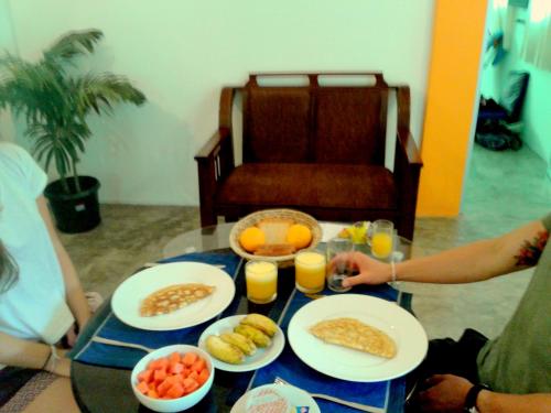 un groupe de personnes assises autour d'une table avec des aliments pour le petit-déjeuner dans l'établissement Dams Place, à Galle