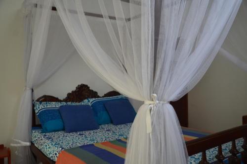 a bedroom with a bed with a white curtain at Dams Place in Galle