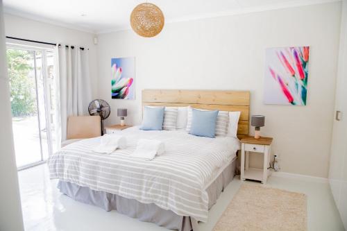 a white bedroom with a large bed with blue pillows at Lemon Tree House in Plettenberg Bay