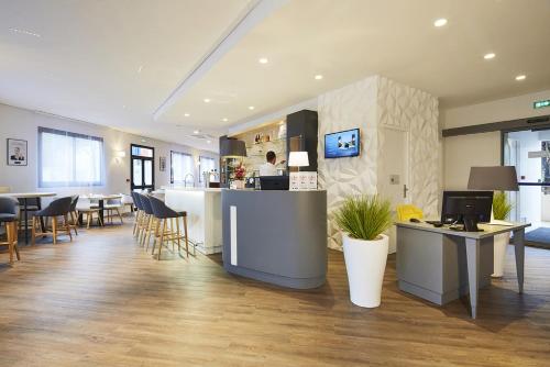 a lobby with a counter and a person in a kitchen at Kyriad Paris Ouest - Bezons La Défense in Bezons