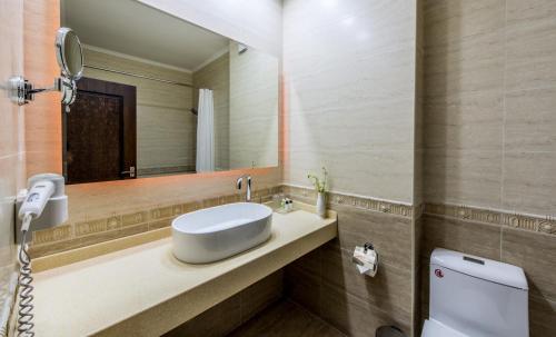 a bathroom with a sink and a toilet and a mirror at Orient Star Hotel in Samarkand