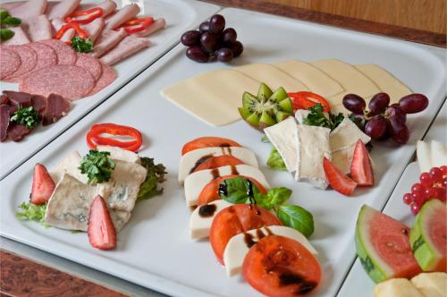 a white plate filled with different types of cheese and fruit at Panoramahotel & Restaurant am Marienturm in Rudolstadt