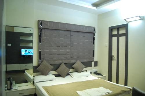 a bedroom with a large bed with a large headboard at Hotel Purva in Indore