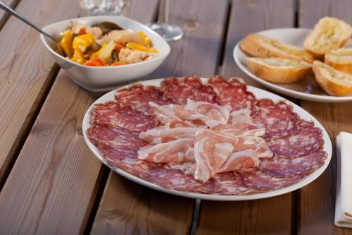 a table with a plate of meat and a bowl of food at Agriturismo con Cucina tipica Nuova Scardua in Cavriana