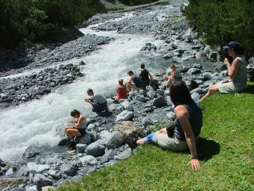 a group of people sitting on rocks by a river at Hotel Madatsch in Trafoi