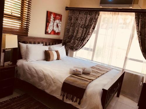 a bedroom with a bed with pillows and a window at Jay and Bee Guesthouse in Durban