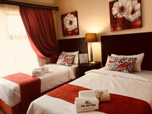 a hotel room with two beds and a window at Jay and Bee Guesthouse in Durban