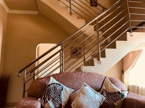 a couch with pillows sitting under a staircase at Jay and Bee Guesthouse in Durban