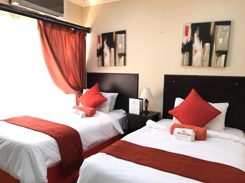 a hotel room with two beds with red pillows at Jay and Bee Guesthouse in Durban