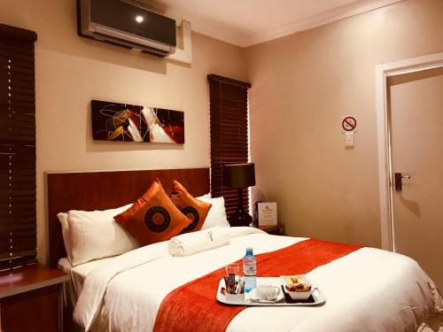 a bedroom with a bed with a tray of food on it at Jay and Bee Guesthouse in Durban