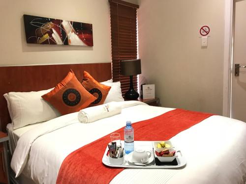 a hotel room with a bed with a tray of food on it at Jay and Bee Guesthouse in Durban