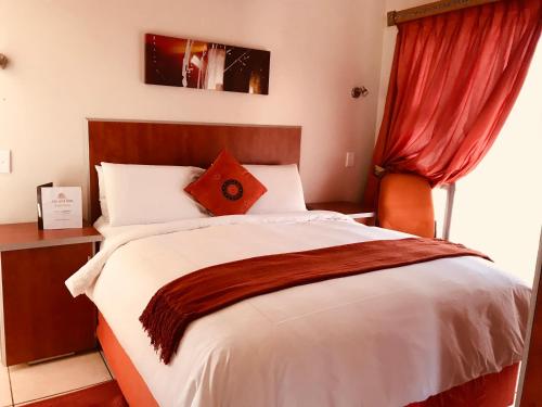 a bedroom with a large bed with a red curtain at Jay and Bee Guesthouse in Durban