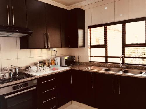 a kitchen with black cabinets and a sink at Jay and Bee Guesthouse in Durban