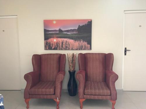 two chairs and a vase with a painting on the wall at Jay and Bee Guesthouse in Durban