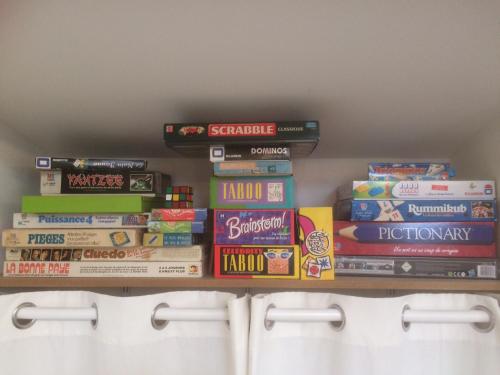 a shelf filled with lots of games and books at Les chambres d'hôtes de Pascale in Mios