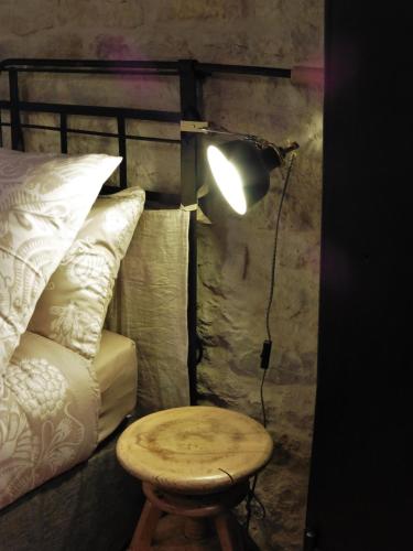 a lamp with a table next to a bed at Chambres d'hôtes Béred Vuillemin in Baume-les-Dames