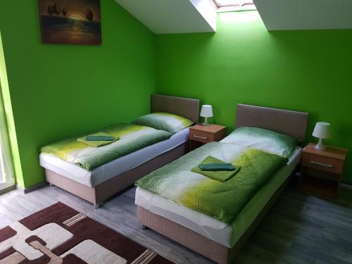 two beds in a room with green walls at Ubytovanie House in Galanta