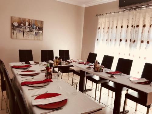 a conference room with long tables and chairs with red napkins at Jay and Bee Guesthouse in Durban
