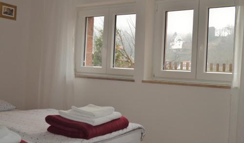 a bedroom with three windows and towels on a bed at Panorama-Blick Miltenberg, 3 Pers., zentr., am Main, Terrasse, Bootverleih, P in Miltenberg