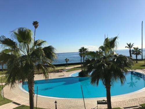 a swimming pool with palm trees in front of the ocean at Marina beach appartement, M'diq Ave, Tetouan in Tetouan