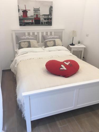 Una cama blanca con una almohada de corazón roja. en The shabby house, en Anzio