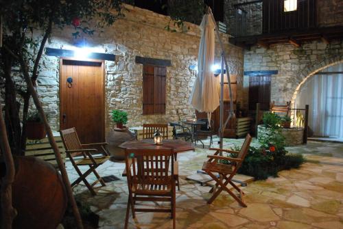 un patio con sillas, mesa y sombrilla en Vavla Rustic Retreat, en Vavla