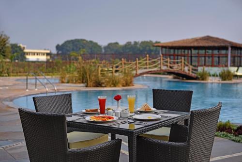 a table with food and drinks on it next to a pool at The Baagh Ananta Elite Ranthambore in Sawāi Mādhopur