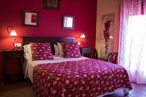 a red bedroom with a bed with pink sheets and pillows at Casa Rural Alquería de Segovia in Tizneros