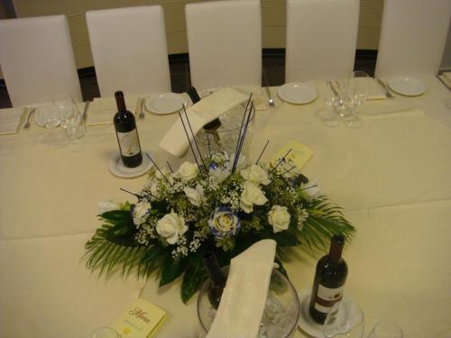 a table with a centerpiece of white flowers and wine bottles at Santa Loja Hotel Residence in Tito