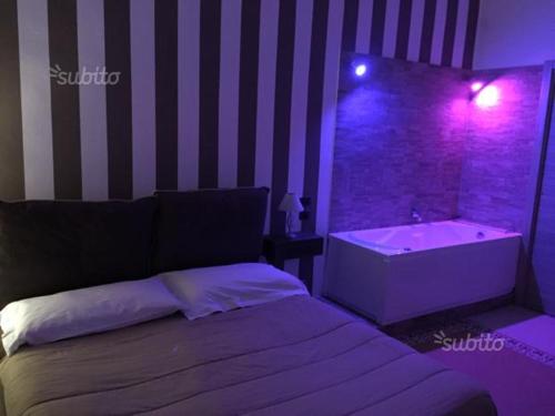 a bedroom with a bed and a bathtub with purple lights at Alba Camere in Palermo