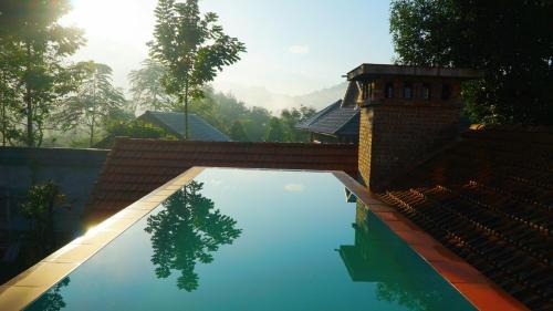a swimming pool with a reflection of a tree in the water at Huy Trung Homestay in Bắc Hà