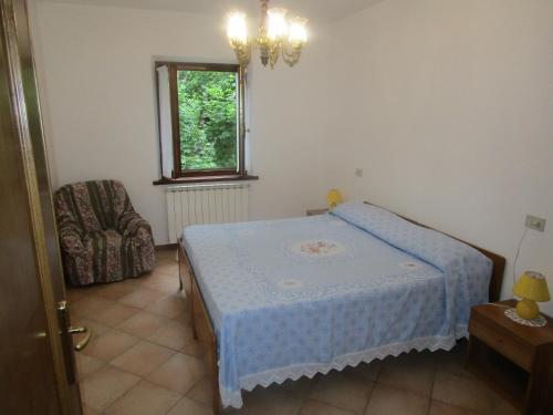 a bedroom with a bed and a chair and a window at appartamenti tra medioevo e natura in Cutigliano