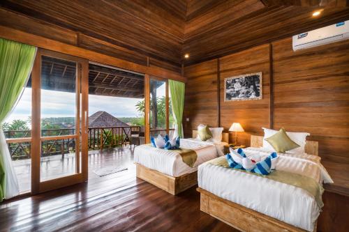 a bedroom with two beds and a balcony at Jenggala Hill in Nusa Lembongan