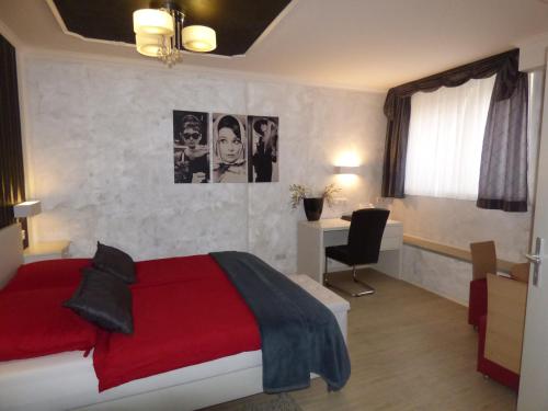 Schlafzimmer mit einem roten Bett und einem Schreibtisch in der Unterkunft Landhaus "Am Sonnenberg" in Diekholzen