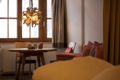 a living room with a table and a chandelier at Am Dorfplatz Suites - Adults friendly in Sankt Anton am Arlberg