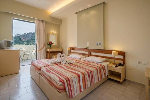 ロダキノにあるPolyrizos Hotelのベッドとバルコニー付きのホテルルーム