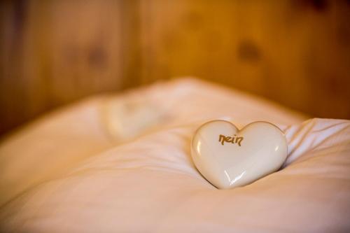 a white heart sitting on top of a bed at Am Dorfplatz Suites - Adults friendly in Sankt Anton am Arlberg