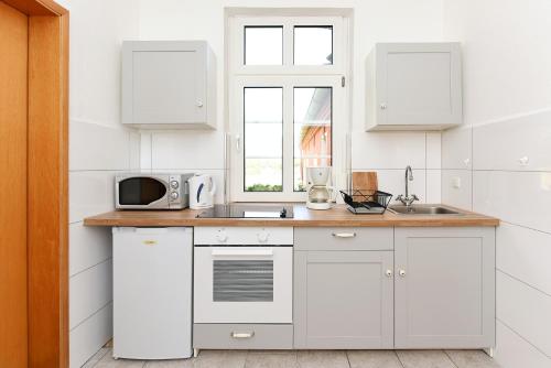 a white kitchen with a sink and a microwave at Landhaus von Felde in Esens