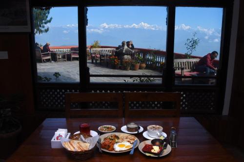 a table with plates of food and a view of the mountains at Peaceful Cottage & Cafe Du Mont in Nagarkot