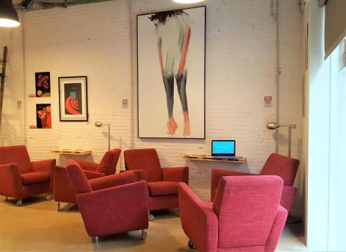 a waiting room with red chairs and a laptop at Ten To Go Hostel in Barcelona