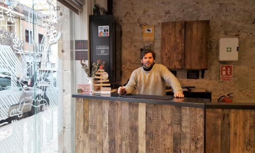 a man standing behind a counter in a kitchen at Ten To Go Hostel in Barcelona