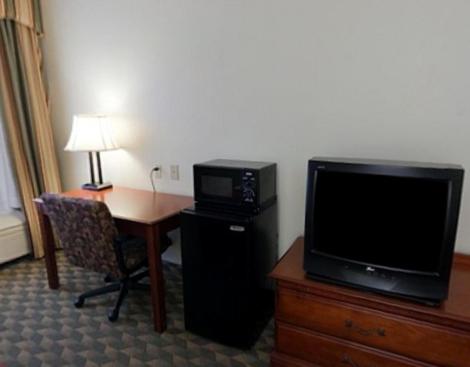 a hotel room with a desk with a television and a deskictericter at Holiday Inn Express Hotel & Suites Laurinburg by IHG in Laurinburg
