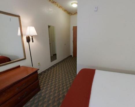 a bedroom with a bed and a dresser and a mirror at Holiday Inn Express Hotel & Suites Laurinburg by IHG in Laurinburg