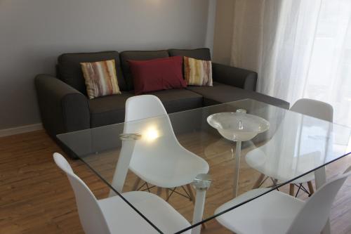 a living room with a glass table and white chairs at Apartamento Copacabana in Estoril