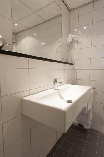 a white bathroom with a sink and a mirror at Eurohotel in Leeuwarden