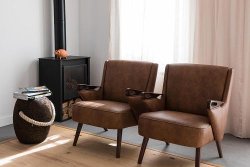 two brown chairs in a living room with a fireplace at Craveiral Farmhouse by Belong Staying & Feeling in São Teotónio